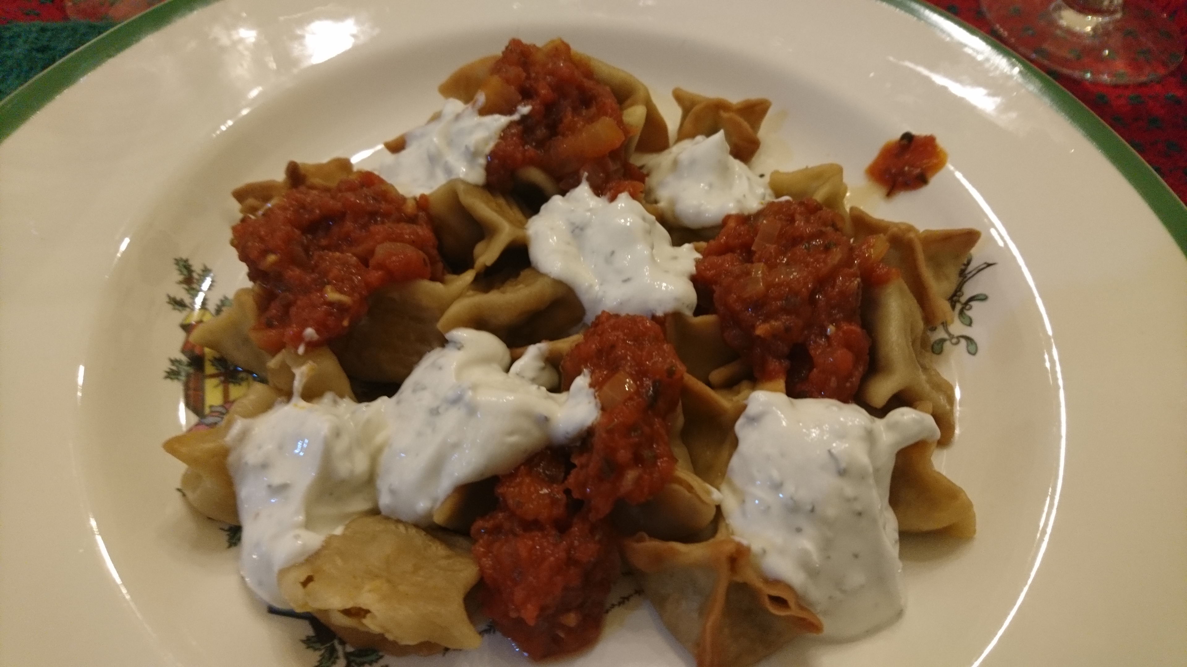 plate of manti with yogurt and tomato sauce