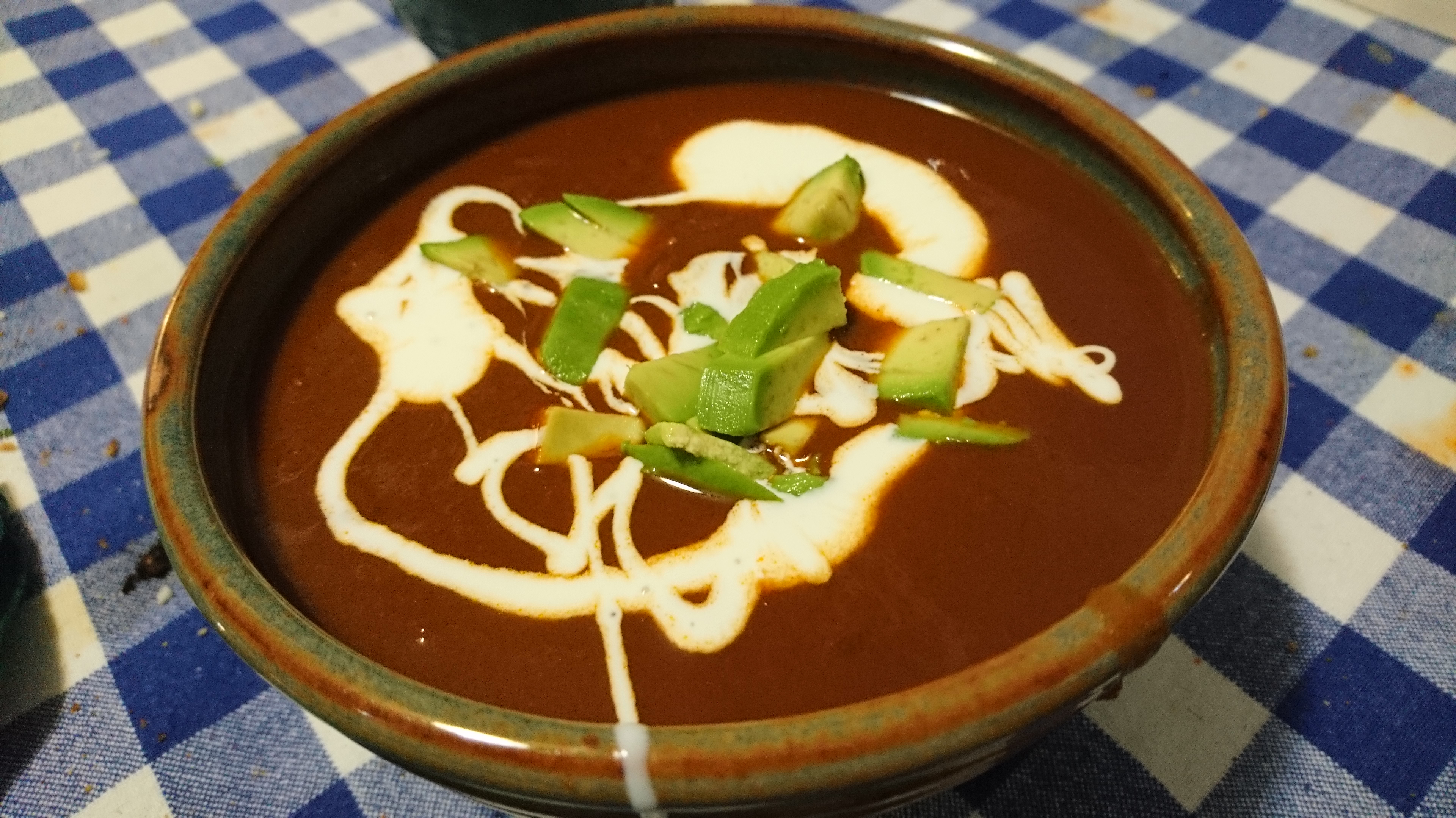 bowl of pinto bean soup with avocado and cream