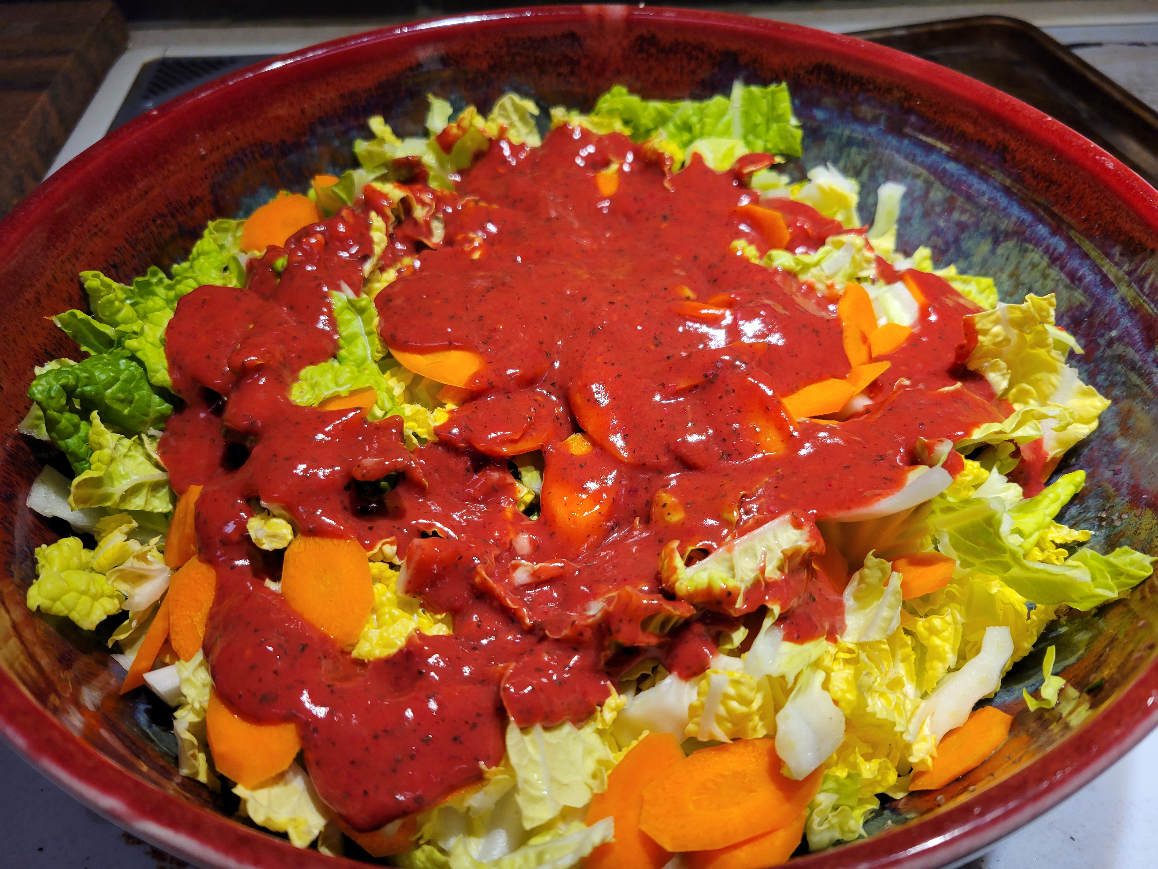 big bowl of cabbage salad with bright red raspberry dressing