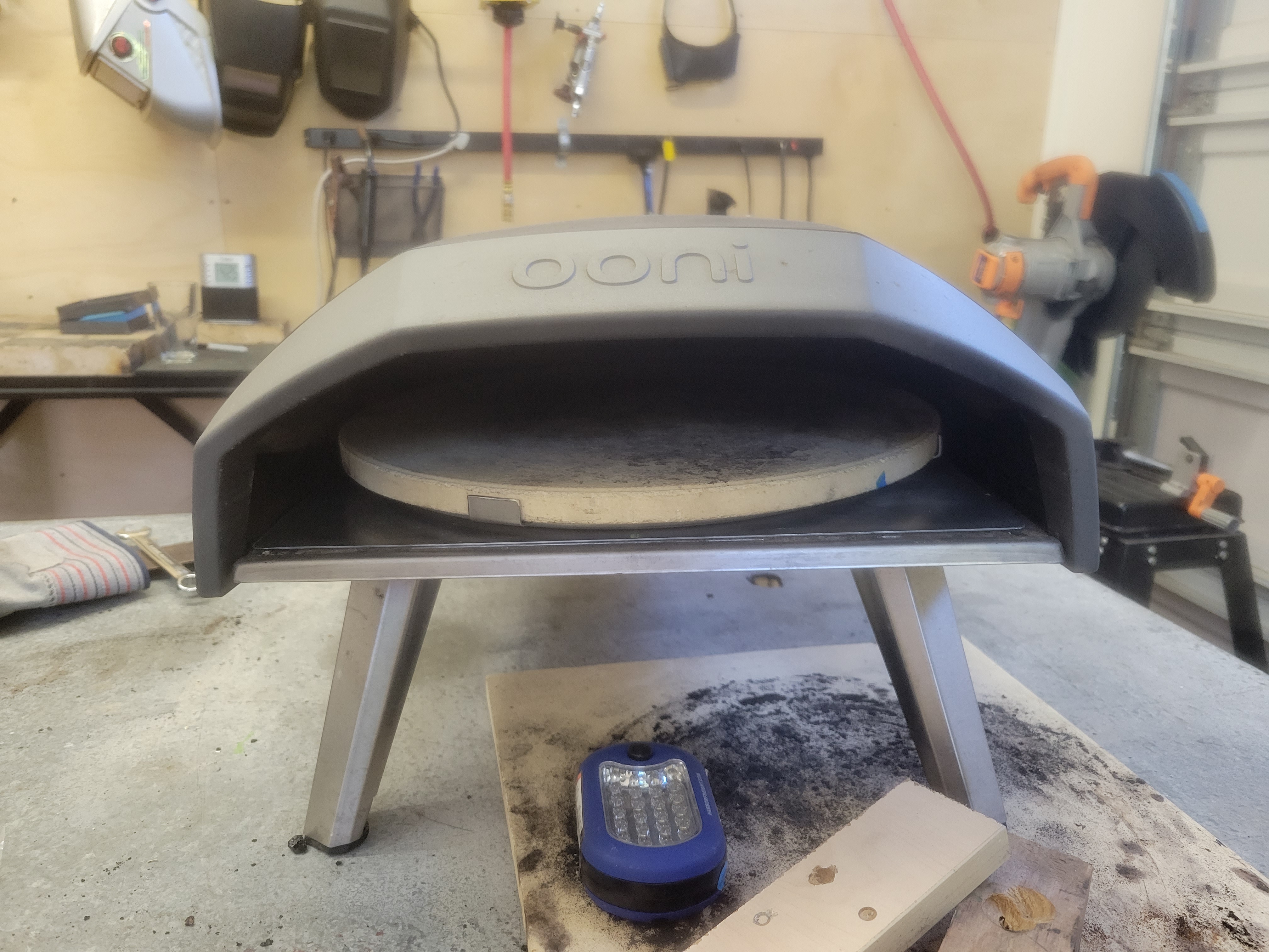 pizza oven with homemade turntable in it, in a metal shop
